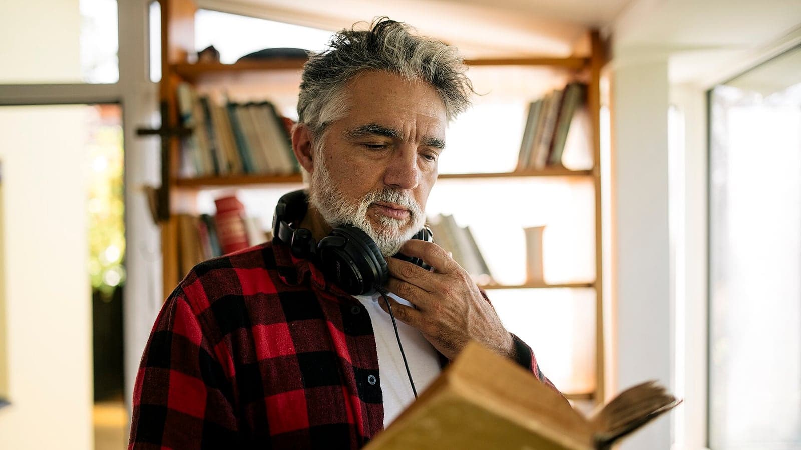 Учащийся слушает материал в наушниках и читает книгу