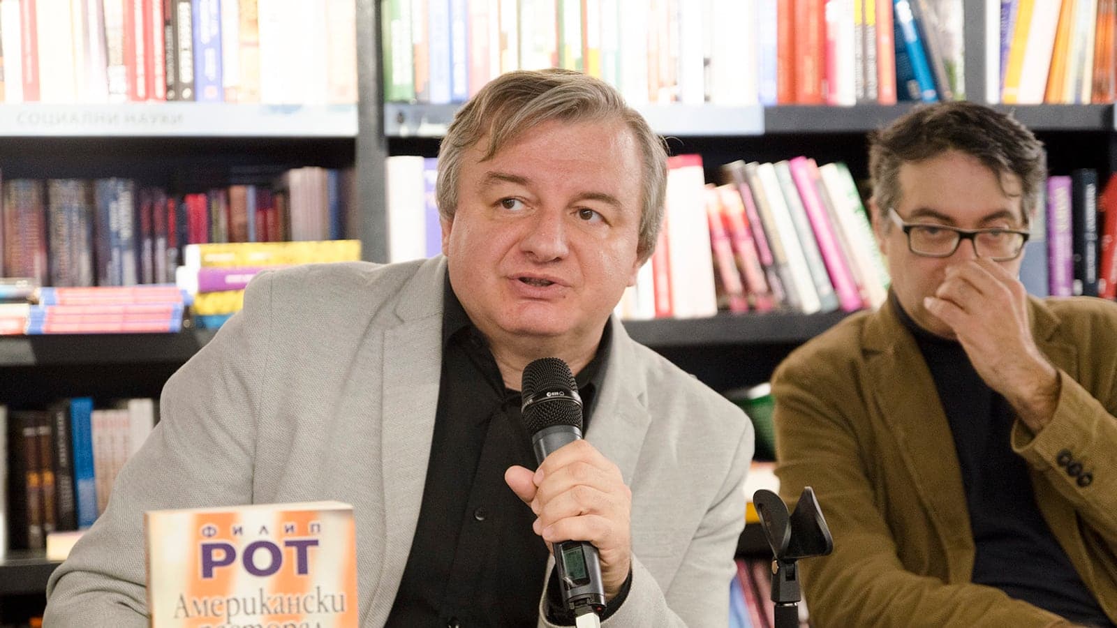 Пламен Дойнов говорит рядом с книгой Филипа Рота на встрече Нового болгарского университета